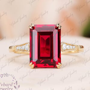 以下が含まれることがあります： エメラルドカットの大きなルビーと、バンドに小さなダイヤモンドがセットされたゴールドのリングです。