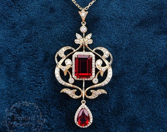 May include: A gold pendant necklace with a large red gemstone and smaller diamonds. The pendant features a detailed, ornate design.