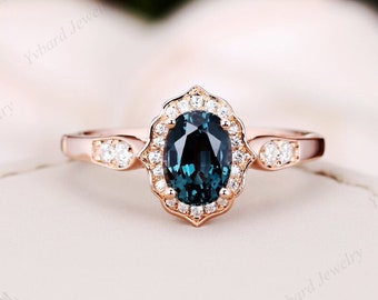 May include: A rose gold engagement ring with a teal oval-shaped gemstone surrounded by a halo of smaller diamonds. The ring has a delicate band with two small diamonds on each side of the center stone.
