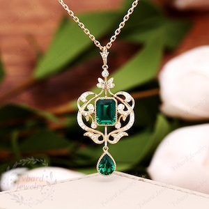 May include: A gold necklace with a green emerald pendant. The pendant features a square emerald stone surrounded by smaller diamonds and a teardrop-shaped emerald dangling below.