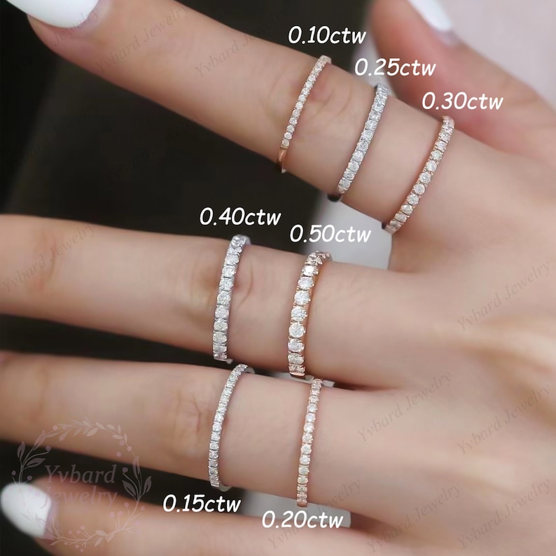 Puede incluir: Primer plano de una mano con un juego de diez anillos de eternidad de diamantes de diferentes tama&ntilde;os, que van desde 0,10 quilates hasta 0,50 quilates. Los anillos est&aacute;n engastados en un engaste de garras cl&aacute;sico y est&aacute;n hechos de oro.