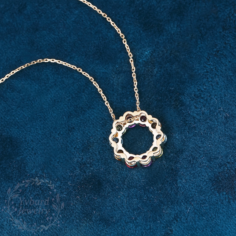 May include: A gold necklace with a circular pendant featuring a rainbow of colorful gemstones. The pendant is made of gold and has a delicate, intricate design.