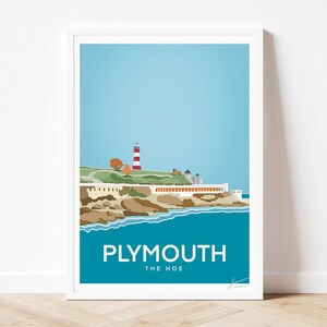 May include: A framed art print featuring a stylized illustration of the Plymouth Hoe coastline, including a red and white striped lighthouse, rocky cliffs, and blue water. The text PLYMOUTH THE HOE is printed in white at the bottom of the image.