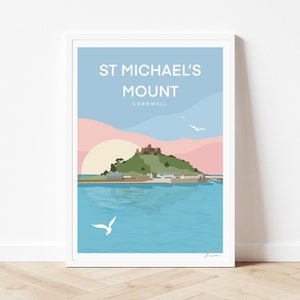 May include: A framed art print featuring a stylized illustration of St. Michael's Mount in Cornwall. The design displays a green island with a castle, a pale yellow sun, pink clouds, and blue water with white seagulls and the text ST MICHAEL'S MOUNT CORNWALL.