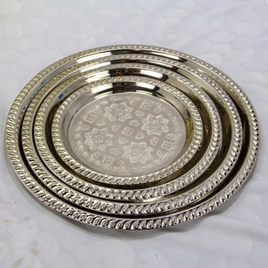 Peut inclure: Ensemble de trois plateaux de service en m&eacute;tal argent&eacute; avec un motif gaufr&eacute; d&eacute;coratif. Les plateaux sont imbriqu&eacute;s les uns dans les autres.