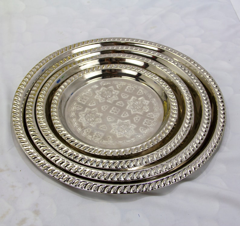 Peut inclure: Ensemble de trois plateaux de service en m&eacute;tal argent&eacute; avec un motif gaufr&eacute; d&eacute;coratif. Les plateaux sont imbriqu&eacute;s les uns dans les autres.