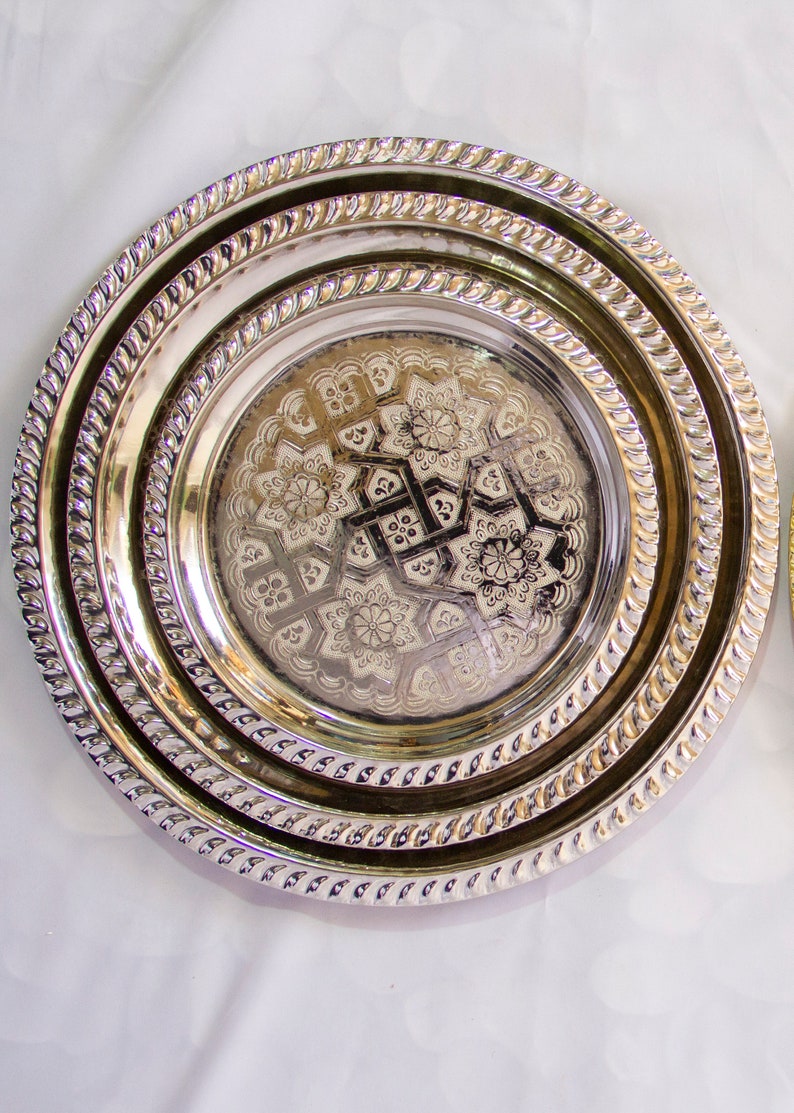 Peut inclure: Un ensemble de trois plateaux de service en argent plaqu&eacute; avec des motifs en relief complexes. Les plateaux sont imbriqu&eacute;s, le plus petit plateau pr&eacute;sentant un motif floral.