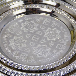 Peut inclure: Un ensemble de trois plateaux de service en argent plaqu&eacute; avec des motifs en relief complexes. Les plateaux sont imbriqu&eacute;s, le plus grand plateau &eacute;tant en bas et le plus petit plateau en haut.
