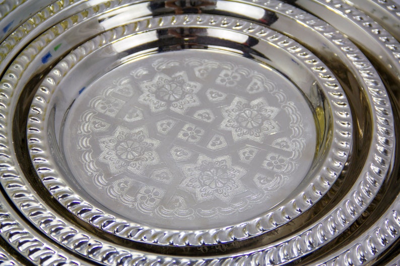 Peut inclure: Un ensemble de trois plateaux de service en argent plaqu&eacute; avec des motifs en relief complexes. Les plateaux sont imbriqu&eacute;s, le plus grand plateau &eacute;tant en bas et le plus petit plateau en haut.