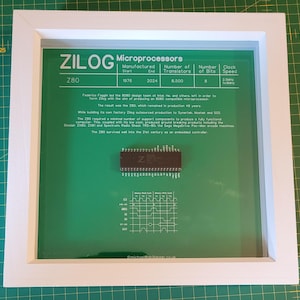 May include: Framed Zilog Z80 Microprocessors display. The white framed display features a green background with text and a Z80 microprocessor chip. The text includes the Zilog logo, the Z80 model, and technical specifications.