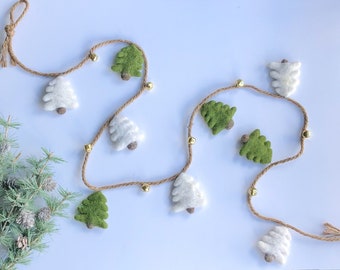 Könnte beinhalten: Eine Girlande aus Filz-Weihnachtsbäumen in Weiß und Grün mit goldenen Glöckchen, die auf einer Schnur aufgefädelt sind.