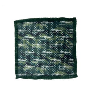 May include: A green camouflage fabric square with the words "Rapid Waves" repeated in white throughout the fabric. The fabric has a mesh texture and is surrounded by a dark green border.