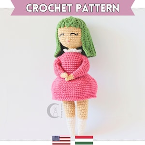 May include: Crochet pattern for a doll with green hair, pink dress, and white shoes. The doll is standing on a white background. The pattern is available in English and Hungarian.