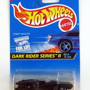 以下が含まれることがあります： ダークライダーシリーズのロゴが付いた、黒いホットウィールダイキャスト製のおもちゃの車。車にはフィンとロケットランプが付いています。パッケージは青で、ホットウィールのロゴと「ストリートビースト」と「生涯保証」の文字が書かれています。