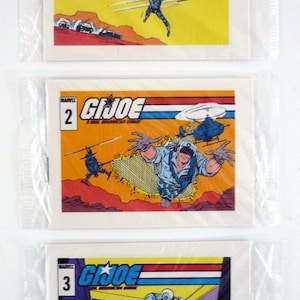 May include: Three vintage G.I. Joe comic book trading cards. The cards are numbered 1, 2, and 3. Each card features a different action scene with G.I. Joe characters. The cards are in good condition with some wear and tear.