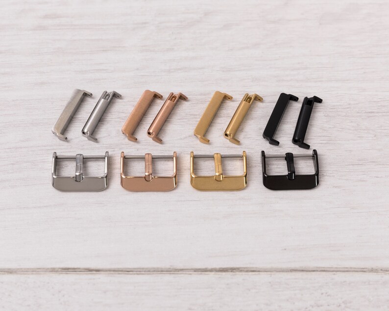 May include: Four pairs of watch strap buckles in different finishes: silver, rose gold, gold, and black. Each buckle is made of metal and has a polished finish.