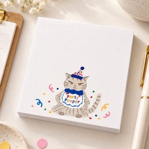 Op de afbeelding: Een vierkant wit notitieblok met een illustratie van een grijze cyperse kat met een blauwe feesthoed met gekleurde stippen en een blauwe vlinderdas. De kat draagt een wit slabbetje met de tekst Party Pooper in gekleurde letters en confetti.