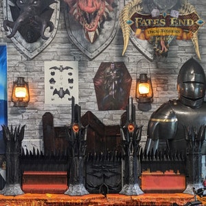 May include: A black metal gate with a red glow behind it. The gate is decorated with spikes and has a skull-like design. The gate is part of a larger set of gates, and there is a knight in armor standing in front of them. The sign above the gate reads "Fates End Dice Towers ML199".