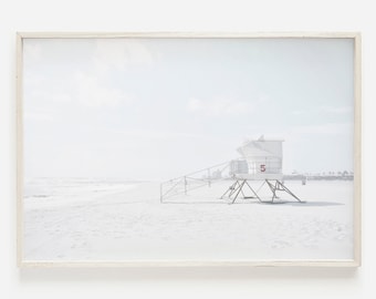 May include: A white lifeguard stand with the number "5" on the side, on a white sandy beach with a blue sky and white clouds in the background.