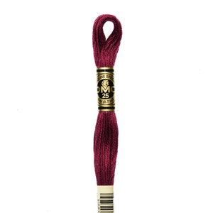May include: A spool of DMC embroidery floss in color 815, a deep burgundy red. The spool is labeled with the DMC logo and the number 25, indicating the length of the floss. The label also includes the text "Speculine" and "3m (8.7 yd)".