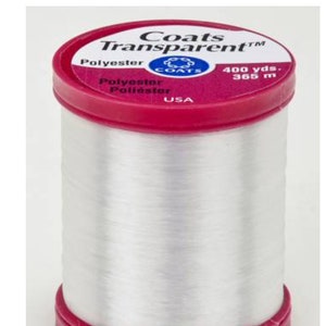 May include: A spool of transparent polyester thread by Coats. The spool has a red top and bottom with the brand name and product details printed on the top. The spool contains 400 yards of thread.
