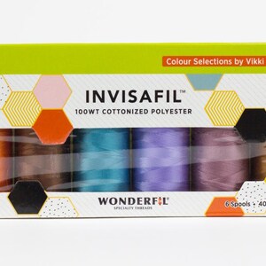 May include: A box of INVISAFIL 100WT cottonized polyester thread spools. The box has a lime green top and a white front with a window showing six spools in various colors. The box is decorated with geometric shapes and the text "Colour Selections by Vikki Pignatelli".