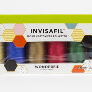 Può includere: Una scatola di rocchetti di filo INVISAFIL in vari colori, tra cui oro, blu, rosso e verde. La scatola ha un design geometrico con il testo "WONDERFIL" e "6 Spools • 400m (437yd)". Il filo è in poliestere cotonizzato 100WT.