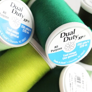May include: Four spools of green thread, two are dark green and two are a lighter shade of green. The spools are labeled "Dual Duty XP" and say "All Purpose" and "250 yds/v 229 m".