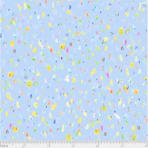 Puede incluir: Una tela azul claro con un patrón de confeti de varios colores, incluyendo amarillo, naranja, rosa, verde y azul. La tela tiene una textura sutil y un aspecto ligeramente descolorido. La tela está marcada con una regla en pulgadas.
