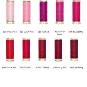 Könnte beinhalten: Eine Sammlung von zehn Garnrollen der Marke Gütermann in verschiedenen Rosa- und Rottönen. Die Rollen sind mit Farbnamen und -nummern beschriftet, darunter "Petal Pink" und "Chili Red". Jede Rolle enthält etwa 100-110 Meter Garn.