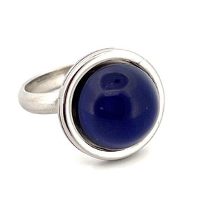 May include: A silver ring with a large, round, dark blue stone set in a double-rimmed bezel.