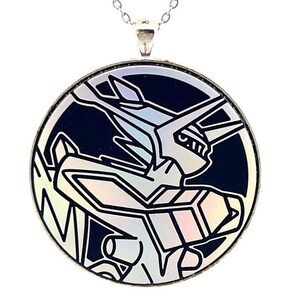 May include: Silver-toned pendant necklace featuring a circular charm with a stylized, iridescent design on a dark blue background. The charm depicts a geometric figure with sharp angles and lines, suspended from a delicate chain.