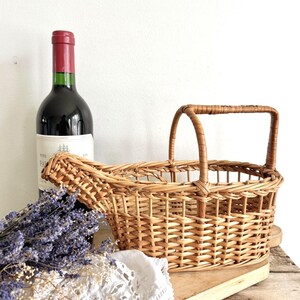 Peut inclure: Un panier en osier tressé avec une poignée, parfait pour transporter une bouteille de vin. Le panier est brun clair et a un aspect naturel et rustique.