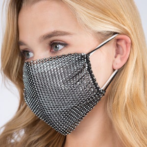 May include: A black face mask with a silver rhinestone mesh design. The mask has elastic ear loops.