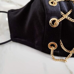 May include: Black velvet face mask with gold chain accents and grommets.