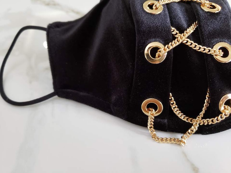 May include: Black velvet face mask with gold chain accents and grommets.