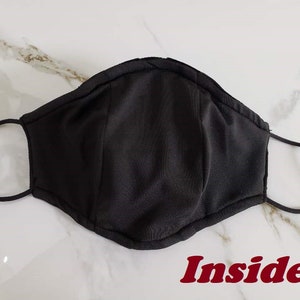 May include: Black fabric face mask with elastic ear loops. The inside of the mask is shown in the image. The word "Inside" is written in red letters below the mask.