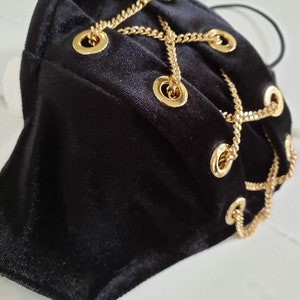 May include: Black velvet face mask with gold chain accents and grommets.