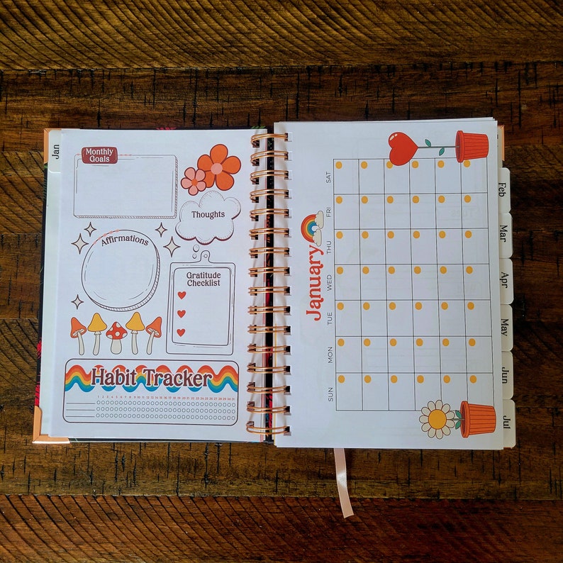 May include: A colorful planner with a monthly calendar, habit tracker, and space for affirmations, thoughts, and a gratitude checklist. The planner has a floral and mushroom theme with a rainbow design.