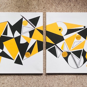 May include: Two abstract paintings on white canvas. Each features geometric shapes in black, yellow, and white, with gold accents. The designs include triangles, circles, and lines, creating a modern art aesthetic.