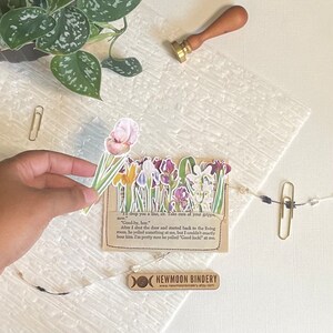 May include: A collection of colorful floral stickers featuring irises, tulips, and other flowers. The stickers are arranged on a brown paper background with text that reads "Til drop you a line, sir. Take care of your grippe, now." "Good-by, boy." "After I shut the door and started back to the living room, he yelled something at me, but I couldn't exactly hear him. I'm pretty sure he yelled "Good luck!" at me."