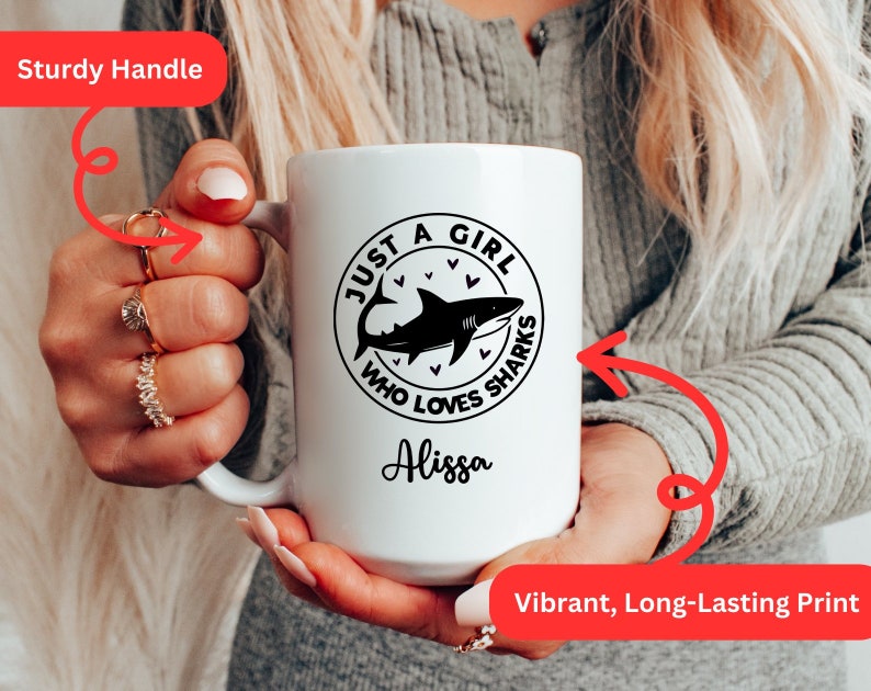 May include: White ceramic mug with a black shark graphic and the text "JUST A GIRL WHO LOVES SHARKS" and the name "Alissa". The mug has a sturdy handle and a vibrant, long-lasting print.