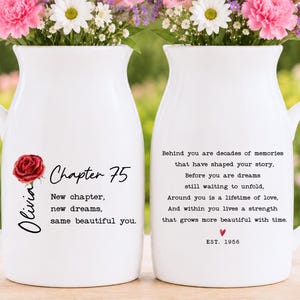 May include: Two white ceramic pitchers featuring floral accents and printed text. The left pitcher displays a red rose, the name Olivia, and the text Chapter 75, New chapter, new dreams, same beautiful you. The right pitcher features a poem and EST. 1956.