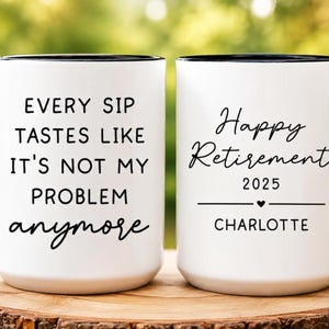 May include: White ceramic coffee mugs with black rims and handles. One mug reads "Every sip tastes like it's not my problem anymore." The other mug says "Happy Retirement 2025" with a heart and the name "Charlotte."
