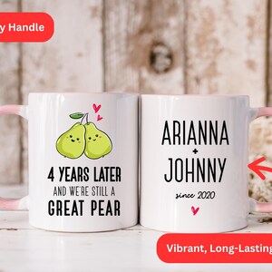 Puede incluir: Taza de cer&aacute;mica blanca con asa rosa. La taza tiene un gr&aacute;fico de dos peras con caras y el texto "4 years later and we're still a great pear". El otro lado de la taza tiene el texto "Arianna + Johnny since 2020".