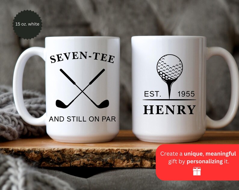 May include: Two white ceramic golf mugs. One mug features crossed golf clubs with the text "SEVEN-TEE AND STILL ON PAR." The other mug has a golf ball design with "EST. 1955 HENRY." Each mug is 15 oz.