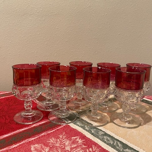 May include: Set of ten clear glass stemmed drinking glasses with a ruby red rim. The glasses have a textured, bubbled design.