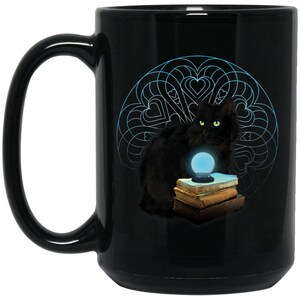May include: Black ceramic mug with a black cat sitting on a stack of books and holding a crystal ball. The cat is surrounded by a blue and white mandala design.