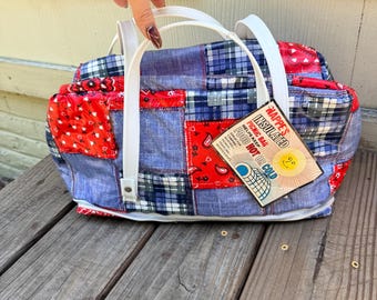 May include: A patchwork picnic bag with white handles. The bag features a mix of red paisley, blue plaid, and denim-like fabrics. A tag reads "Nappe's Insulated Picnic Bag, Helps Keep Food Hot or Cold."