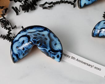 May include: Blue and black ceramic fortune cookies with a white card that reads "happy 9th Anniversary! xoxo".